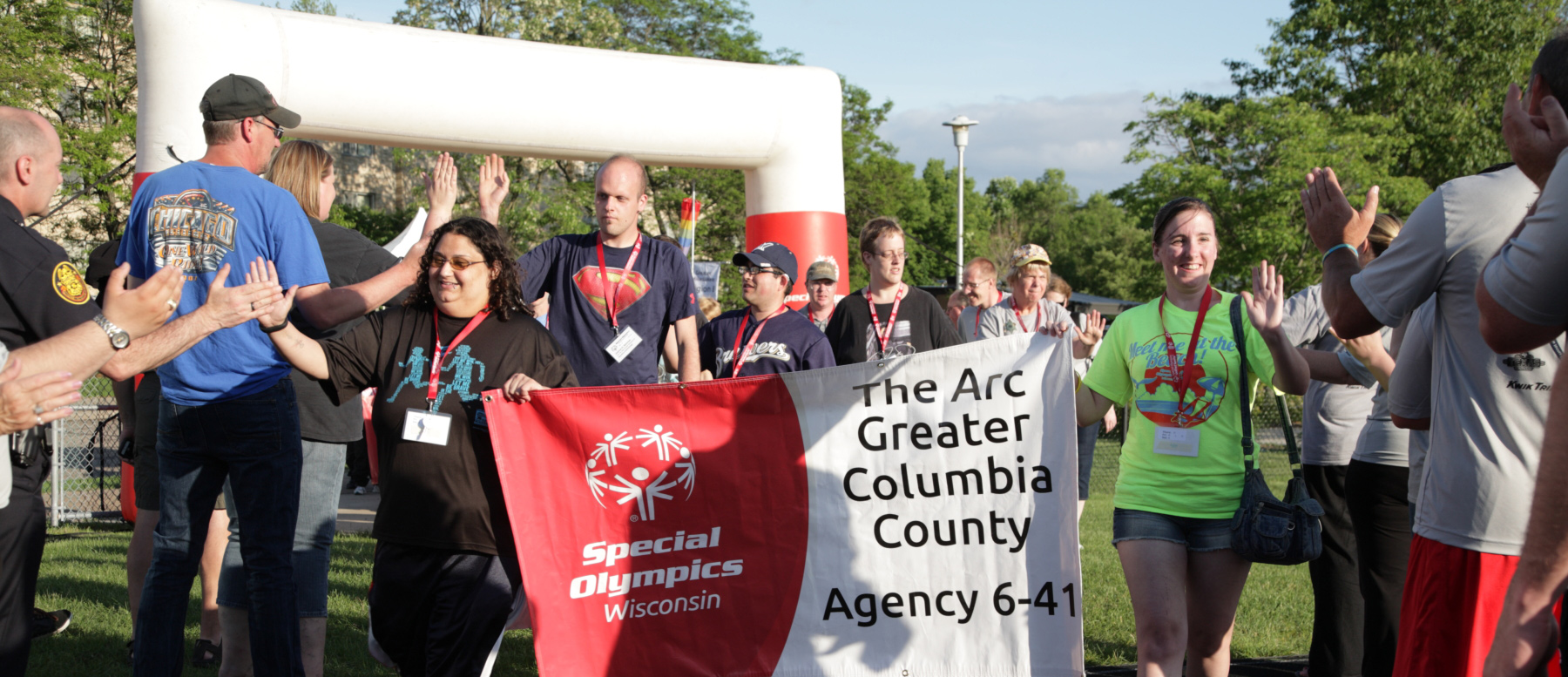 Special Olympic participants getting high fives from crowd as they walk with banner